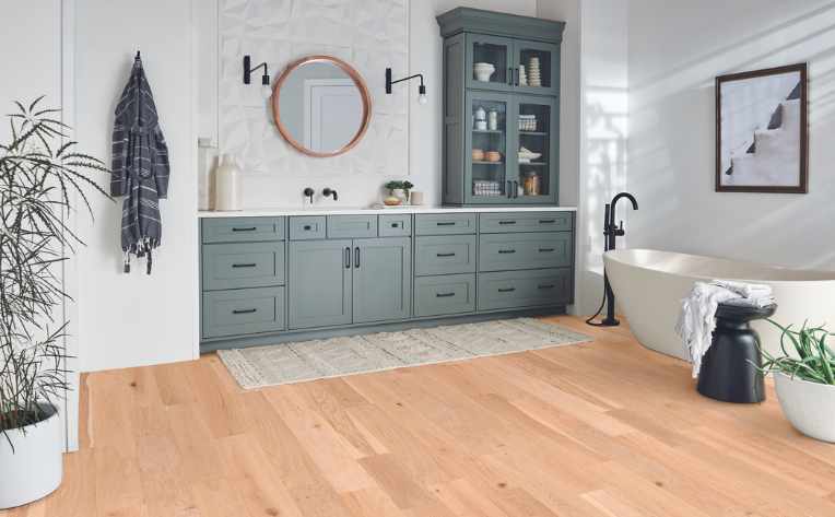 light hardwood floors in bathroom with blue cabinets and natural accents